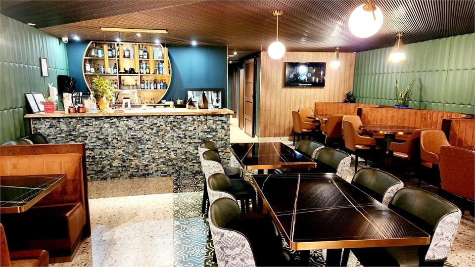 The Aastha dining room with deep green walls and brass pendant lights